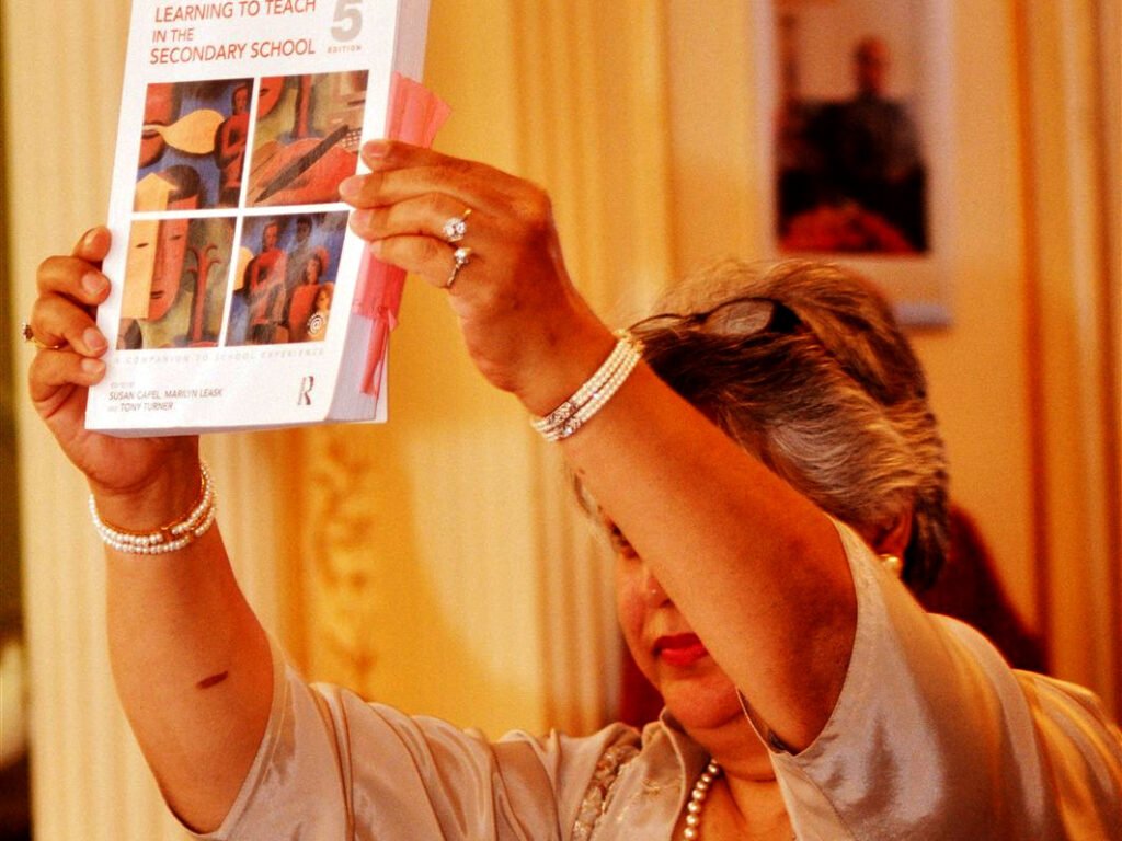 Woman holding up the textbook Learning to Teach in the Secondary School