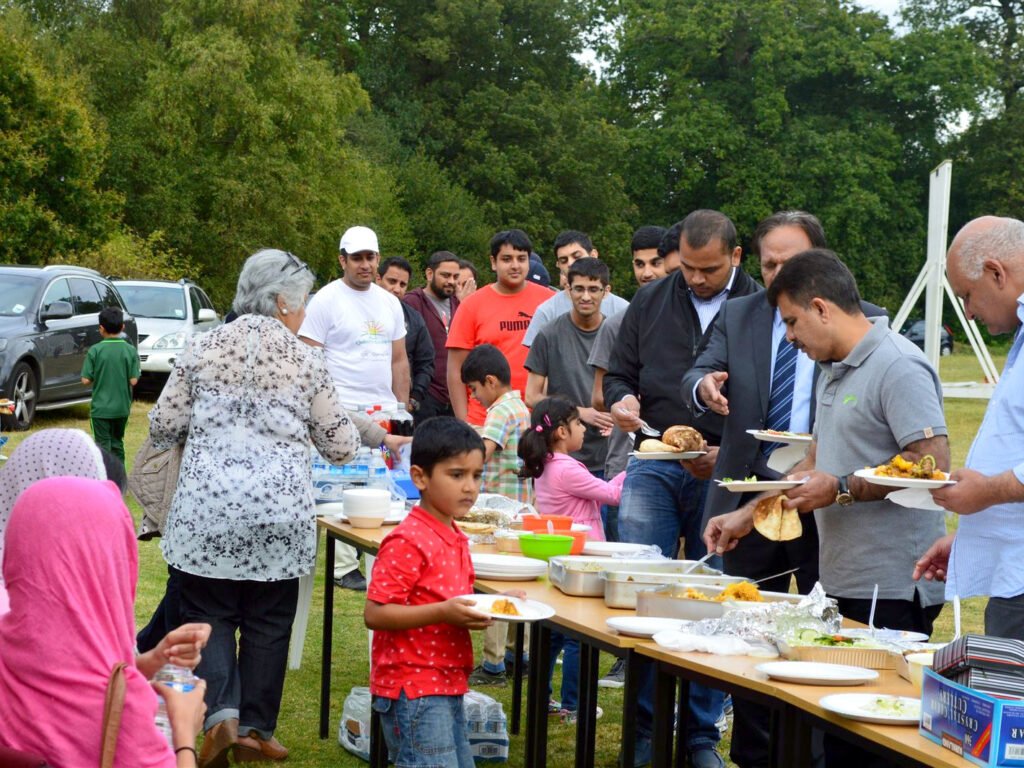 Adults and children queuing with plates at an outdoor buffet table