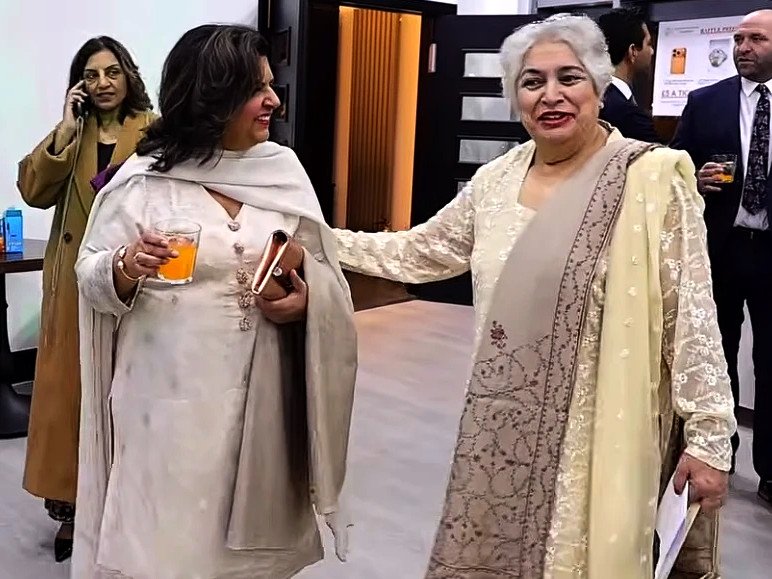 Iffat Ferdinand, in cream embroidered clothing, greets a guest at the QEF Annual Fundraising Dinner in Bradford