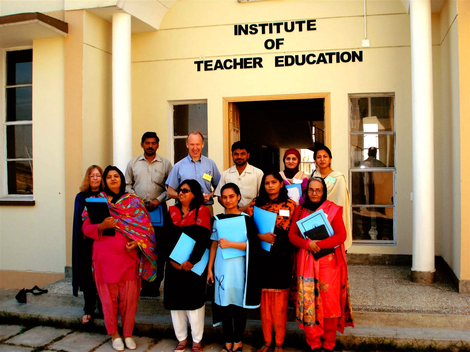 Institute of Teacher Education, 2006-07 Trainees and trainers holding blue folders outside the Institute of Teacher Education sign