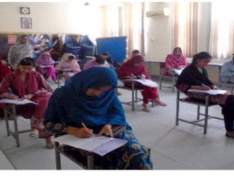 Women trainee teachers writing at desks spaced out in an examination hall