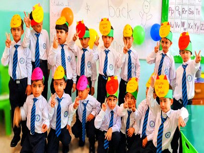 A group of young boys in school uniform wearing colourful paper hats and making victory signs
