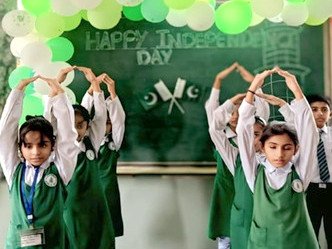 Girls in school uniform forming arches with their arms in front of balloons and a Happy Independence Day board