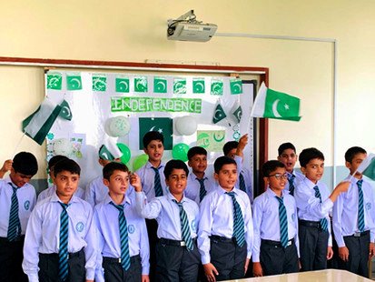 Boys in school uniform standing in rows in a classroom decorated with green and white flags