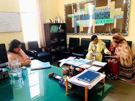 Staff and parents looking through pupils' work at a large desk in a school office
