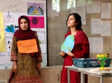 Two young women presenting beside posters about protecting the environment