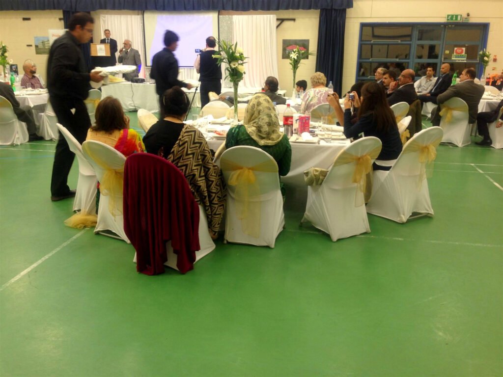 Waiter carrying a tray between tables of guests in a hall
