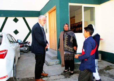 Staff and a pupil prefect welcome a visitor outside a school building