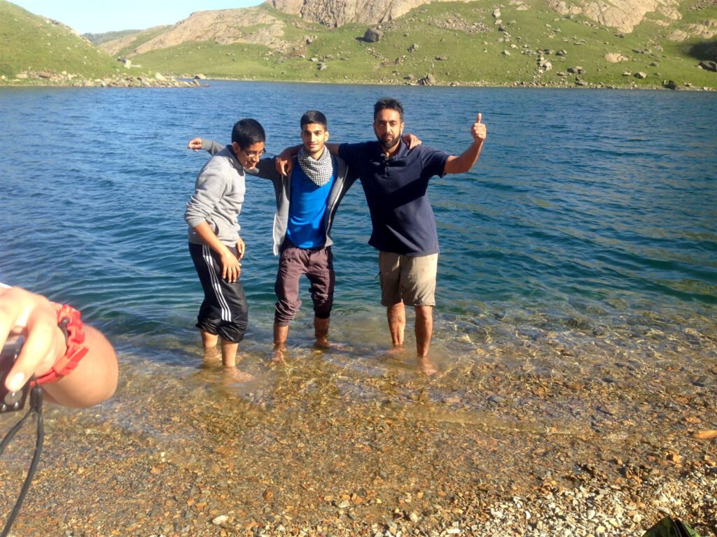 Three walkers standing arm in arm in a shallow lake