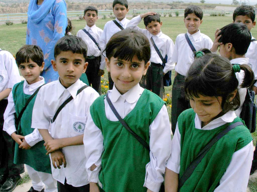 Smiling pupils in green and white school uniform outdoors