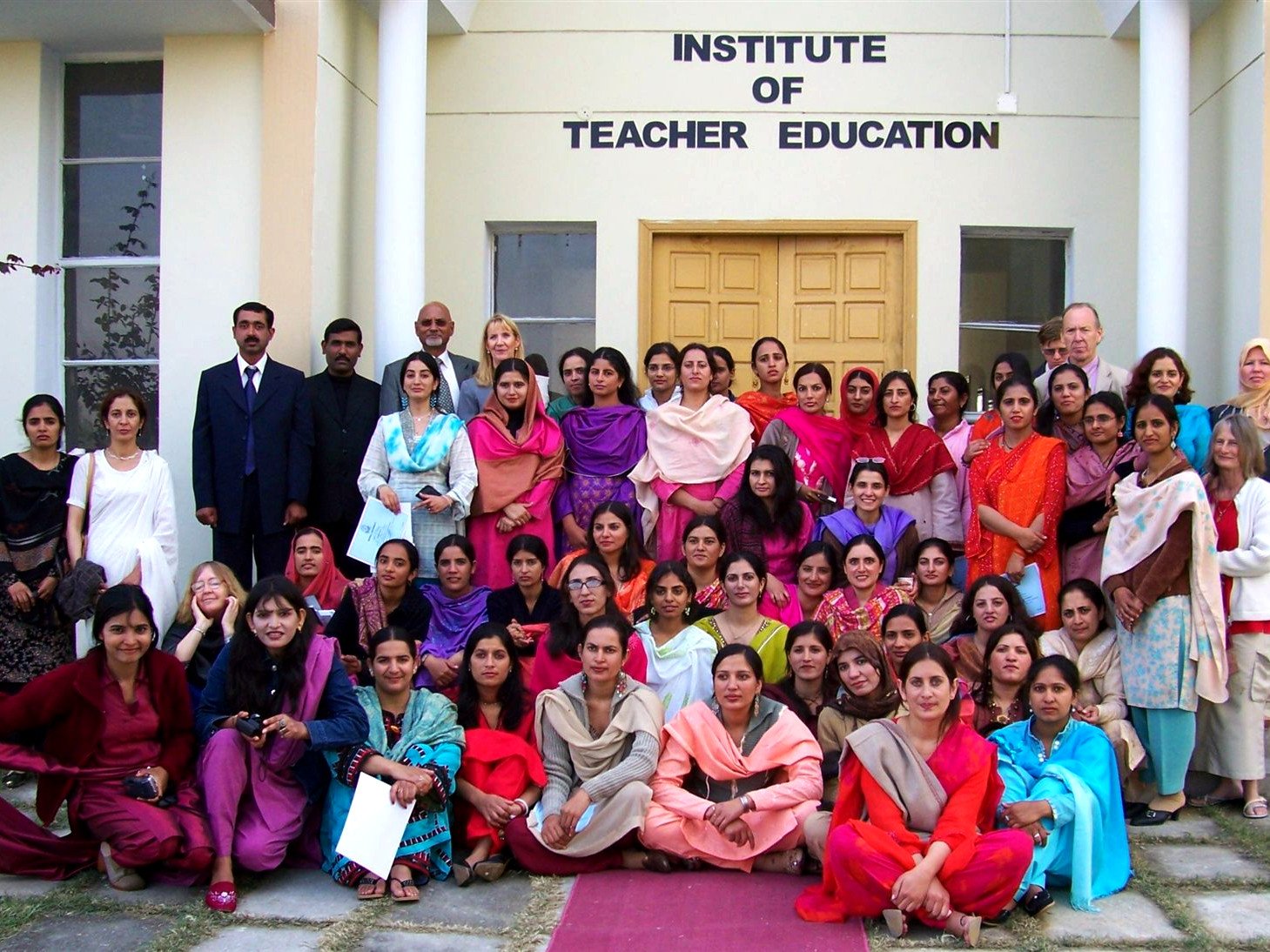 A large group of women trainee teachers and their trainers on the steps of the training institute