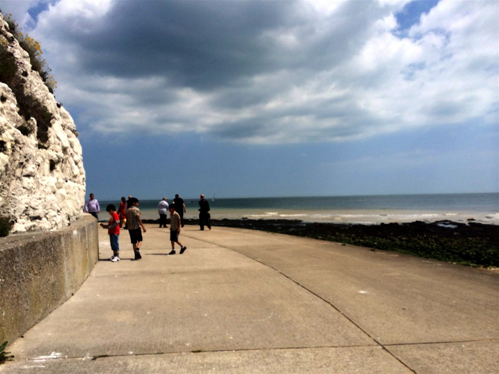Walk4Education, June 2014 Children and adults walking along a promenade beside white chalk cliffs and the sea.